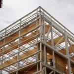 A modern building under construction with steel and wood elements, captured on a cloudy day.